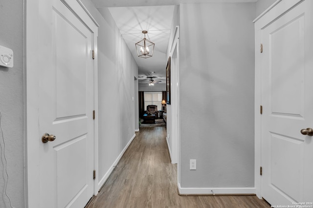 corridor with light hardwood / wood-style flooring and an inviting chandelier