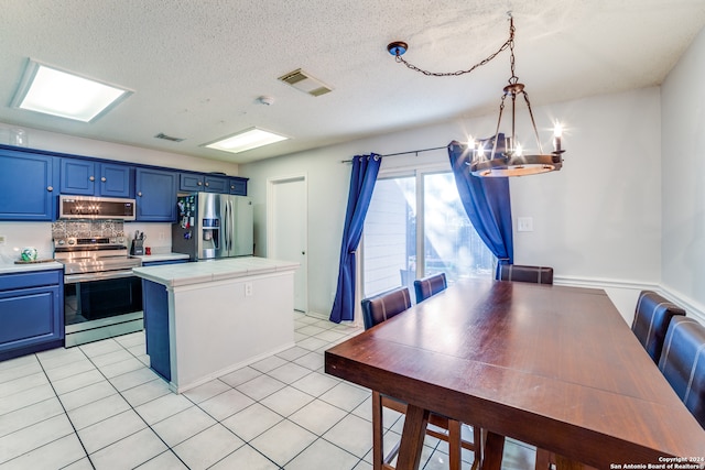 kitchen featuring stainless steel appliances, blue cabinets, a notable chandelier, a center island, and hanging light fixtures