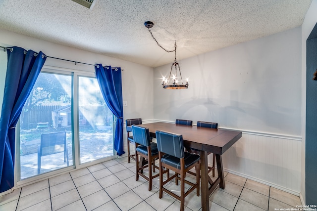 dining area with light tile patterned floors, a textured ceiling, and an inviting chandelier