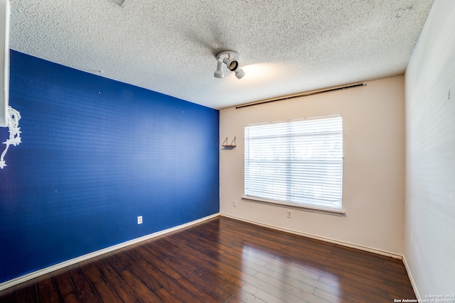 spare room with a textured ceiling and hardwood / wood-style flooring