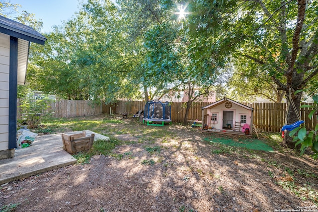 view of yard featuring an outdoor structure and a trampoline