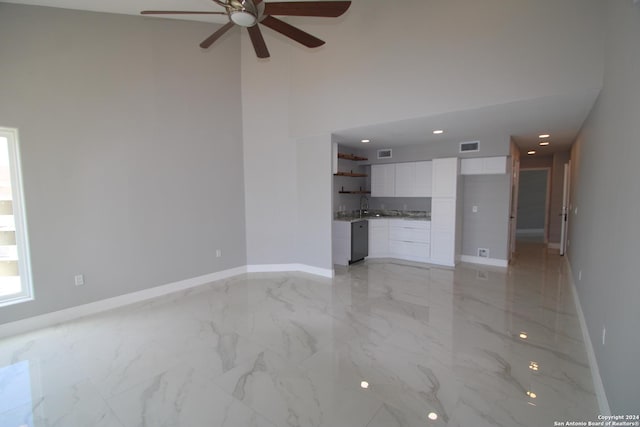 900 Padre Blvd Unit 307, South Padre Island, TX 78597 - unfurnished living room with a ceiling fan, baseboards, a towering ceiling, light marble finish flooring, and a sink