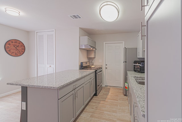 kitchen featuring sink, gray cabinets, light stone countertops, light hardwood / wood-style floors, and stainless steel range with gas stovetop