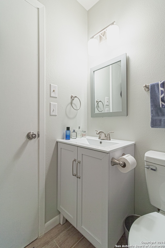 bathroom with hardwood / wood-style flooring, vanity, and toilet