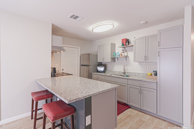 kitchen featuring a kitchen breakfast bar, sink, appliances with stainless steel finishes, and light hardwood / wood-style flooring