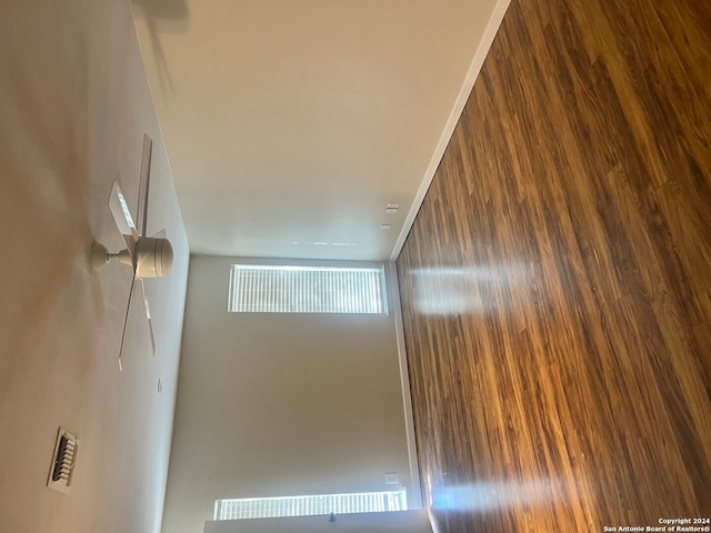 unfurnished room with hardwood / wood-style flooring, crown molding, and wood walls