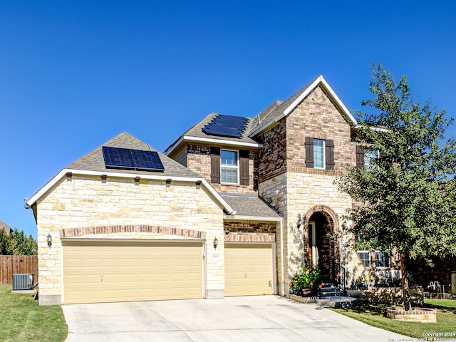 view of front of house featuring central AC unit, solar panels, and a garage