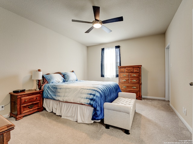 bedroom with a textured ceiling, ceiling fan, and light carpet