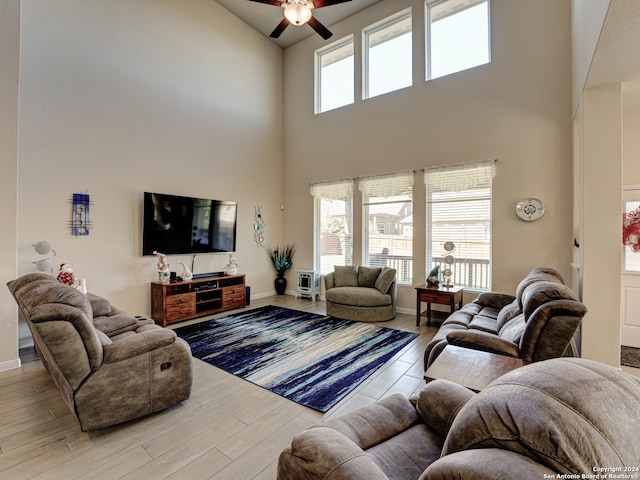 living room featuring a towering ceiling, light hardwood / wood-style flooring, and ceiling fan