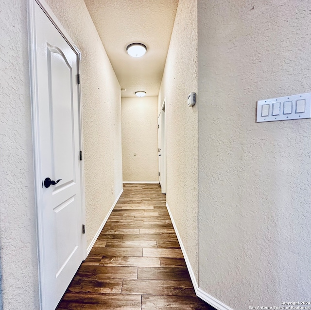 hallway featuring wood-type flooring and a textured ceiling