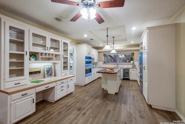 kitchen featuring a center island, light hardwood / wood-style flooring, decorative light fixtures, white cabinetry, and beverage cooler