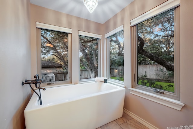 bathroom with tile patterned flooring, a tub to relax in, and a healthy amount of sunlight