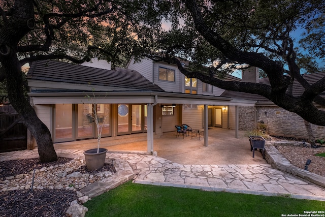 back house at dusk with a patio area