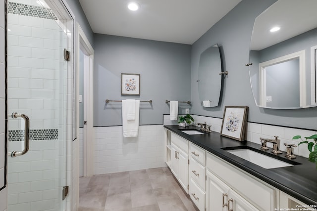 bathroom featuring vanity, tile patterned floors, tile walls, and a shower with shower door