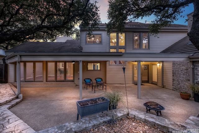 back house at dusk with a fire pit and a patio