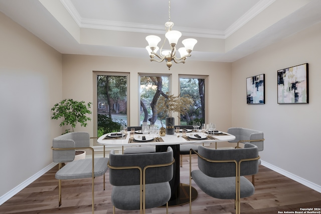 dining space with dark hardwood / wood-style floors, ornamental molding, a tray ceiling, and an inviting chandelier