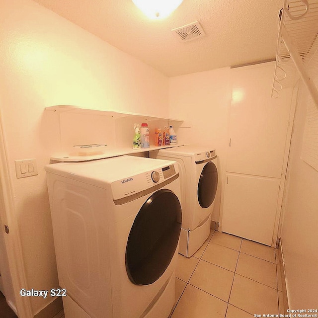 washroom featuring light tile patterned flooring, separate washer and dryer, and a textured ceiling