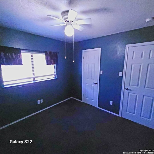 unfurnished bedroom featuring carpet, a textured ceiling, and ceiling fan