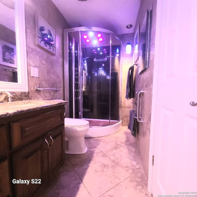 bathroom featuring vanity, toilet, walk in shower, and tile walls