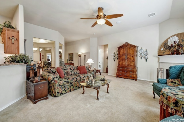 living room with ceiling fan with notable chandelier, light carpet, a tile fireplace, and vaulted ceiling