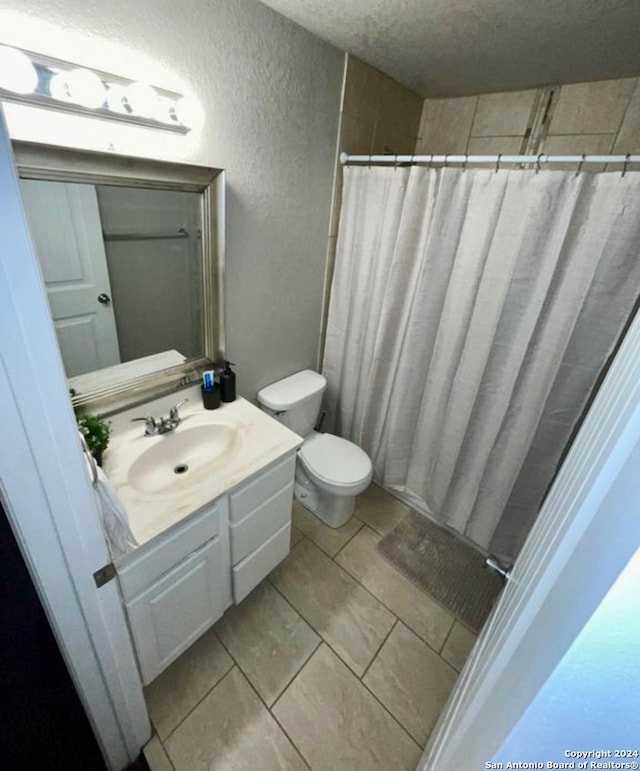 bathroom with a shower with curtain, tile patterned flooring, a textured ceiling, toilet, and vanity