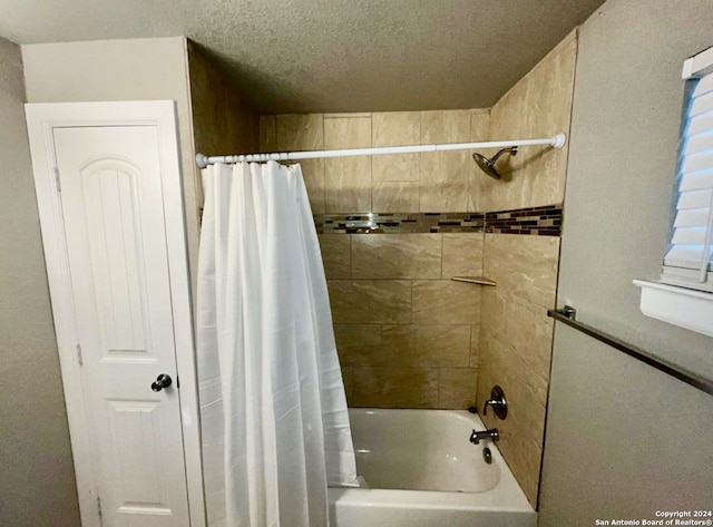 bathroom featuring a textured ceiling and shower / tub combo with curtain