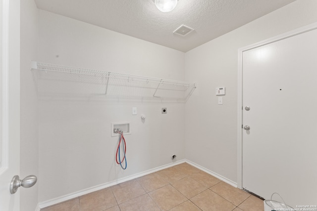 laundry area featuring gas dryer hookup, washer hookup, light tile patterned floors, a textured ceiling, and hookup for an electric dryer