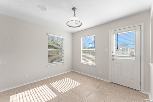 doorway with a textured ceiling and light tile patterned flooring