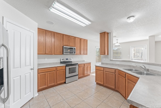 kitchen featuring pendant lighting, sink, light tile patterned floors, a textured ceiling, and stainless steel appliances