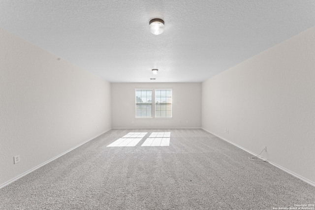 carpeted empty room with a textured ceiling