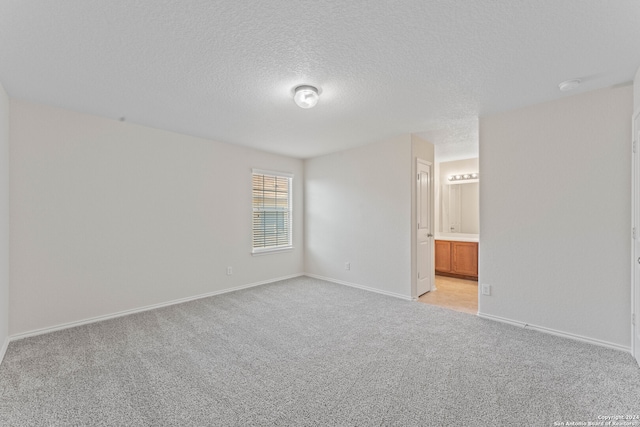 spare room featuring a textured ceiling and light colored carpet