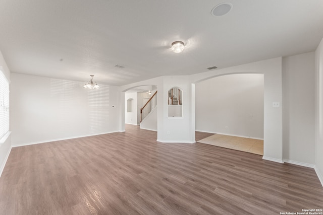 unfurnished living room with hardwood / wood-style floors and a notable chandelier