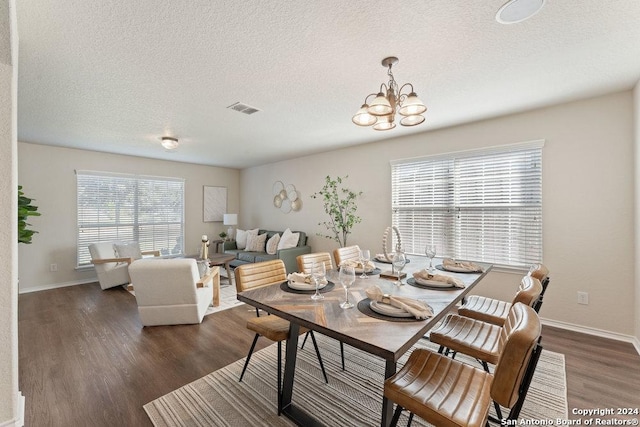 dining area with a textured ceiling, a chandelier, and dark hardwood / wood-style floors