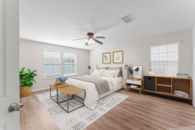 bedroom featuring wood-type flooring, a textured ceiling, and ceiling fan