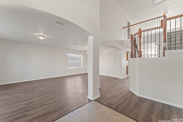 unfurnished living room with wood-type flooring, a textured ceiling, and vaulted ceiling