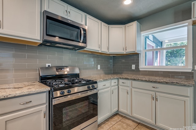 kitchen featuring white cabinets, light tile patterned floors, a textured ceiling, and appliances with stainless steel finishes