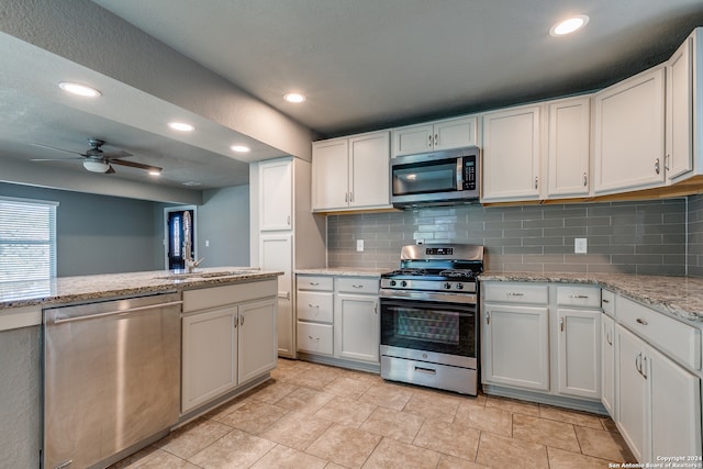 kitchen with white cabinets, sink, ceiling fan, appliances with stainless steel finishes, and light stone counters