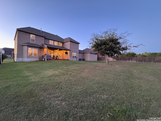 back house at dusk with a lawn