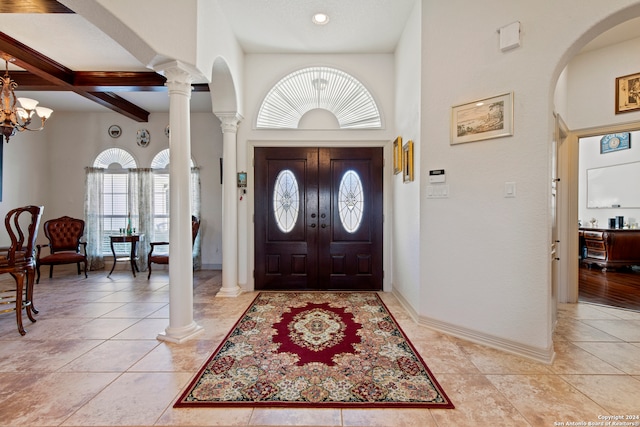 foyer featuring beamed ceiling, a high ceiling, an inviting chandelier, and light tile patterned flooring