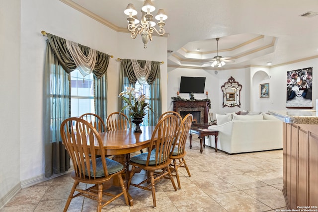 dining space with ceiling fan with notable chandelier, a tray ceiling, crown molding, and light tile patterned flooring