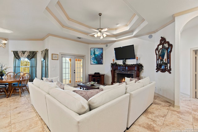 living room featuring ceiling fan, a raised ceiling, ornamental molding, and a fireplace