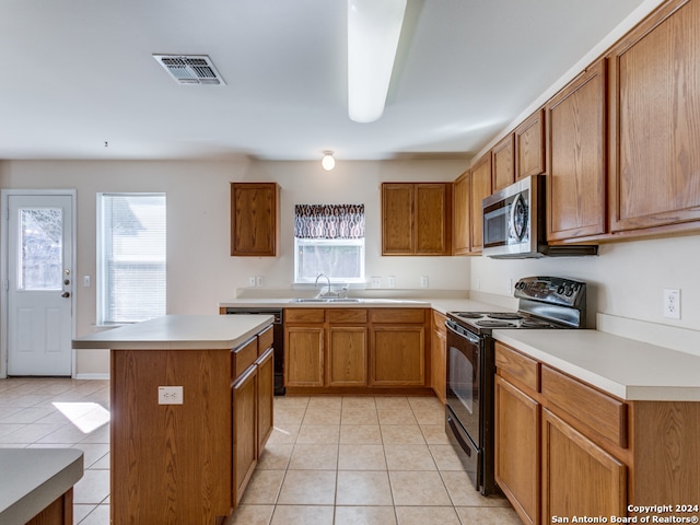 kitchen with light tile patterned floors, sink, a wealth of natural light, and black appliances