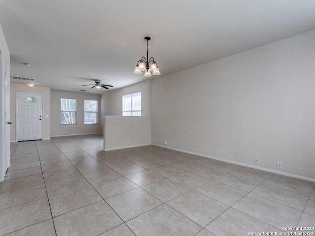 tiled spare room with ceiling fan with notable chandelier