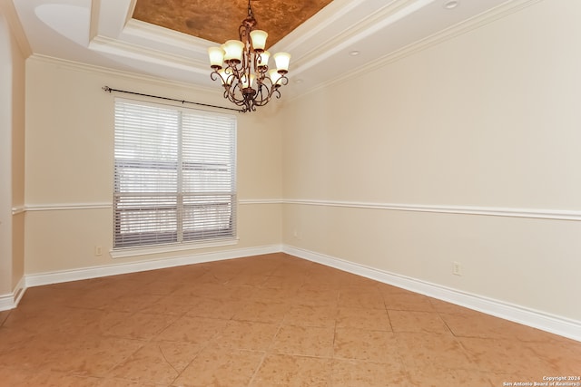 spare room featuring ornamental molding, a raised ceiling, and a notable chandelier