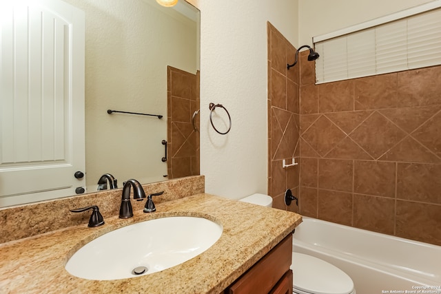 full bathroom featuring tiled shower / bath, vanity, and toilet