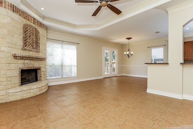 unfurnished living room featuring ceiling fan with notable chandelier, a fireplace, crown molding, and french doors