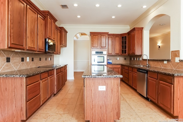 kitchen with a center island, sink, crown molding, dark stone countertops, and stainless steel appliances