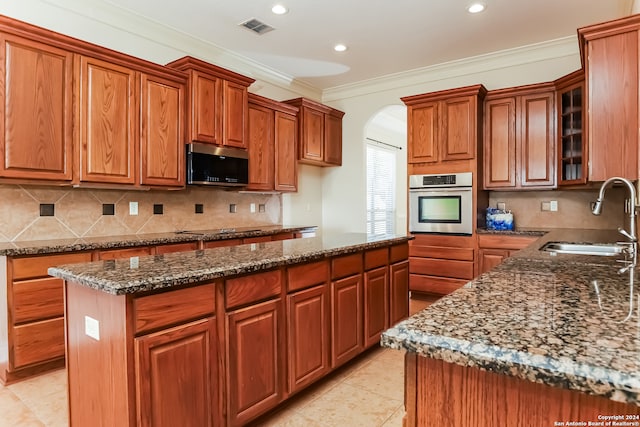 kitchen featuring a center island, sink, appliances with stainless steel finishes, and dark stone counters