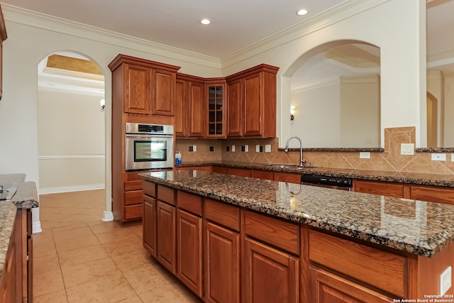 kitchen with appliances with stainless steel finishes, dark stone counters, tasteful backsplash, and ornamental molding