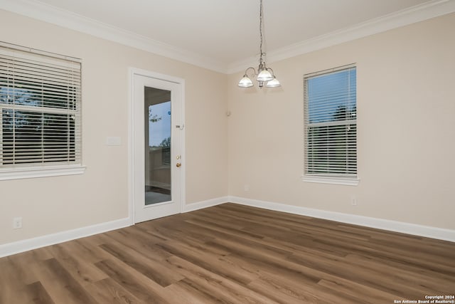 spare room featuring a chandelier, crown molding, and dark wood-type flooring